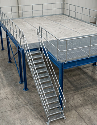 Steel mezzanine platform with secondary beam grid and staircase access inside industrial building